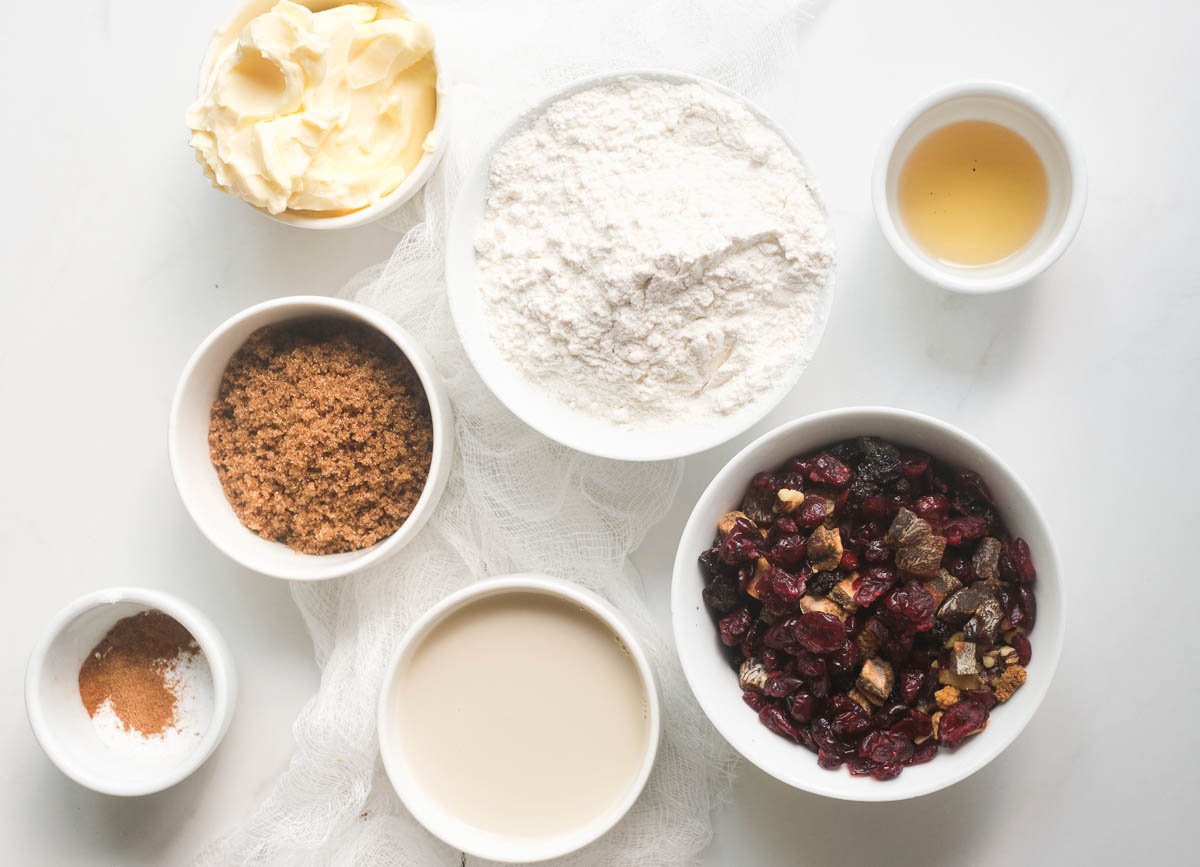 Ingredients for vegan fruit cake: vegan butter, flour, dried fruit and nuts, vanilla extract, vegan buttermilk, brown sugar, and spices. 