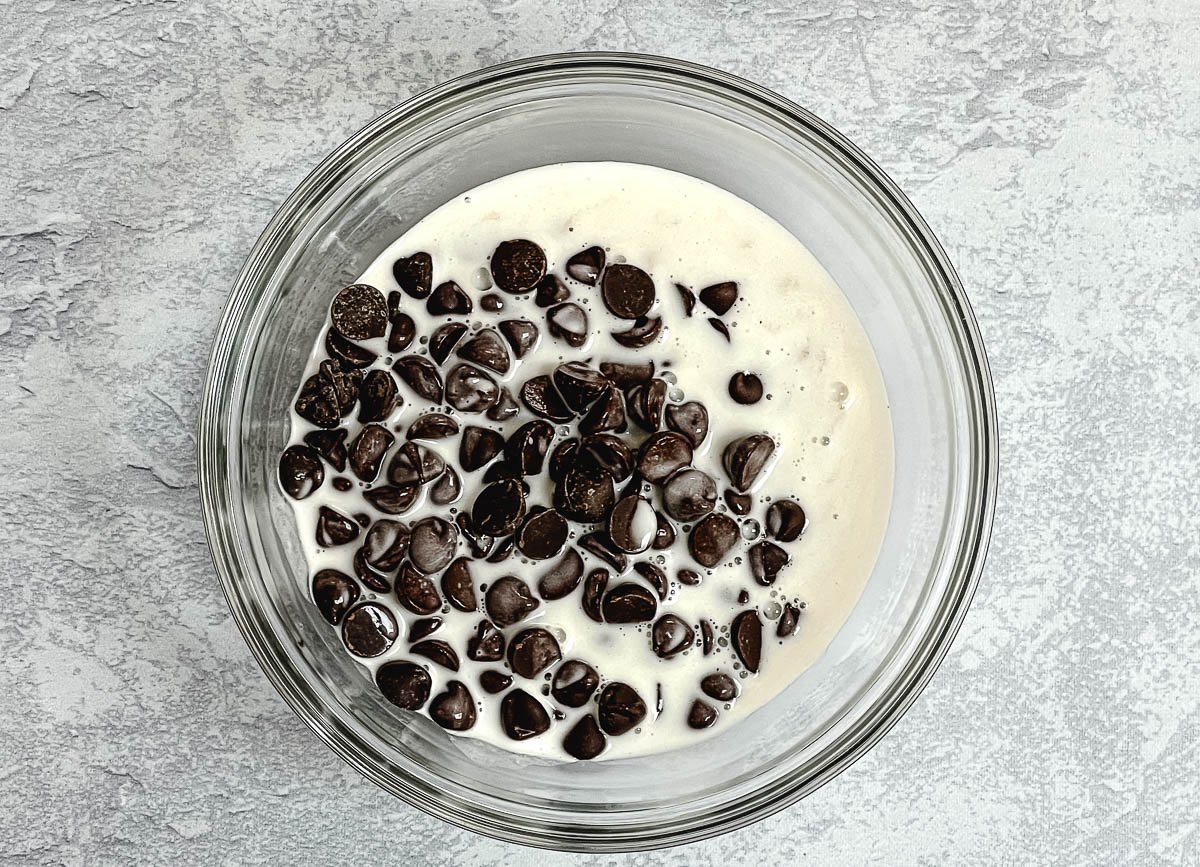 Chocolate chips and coconut milk in glass mixing bowl.