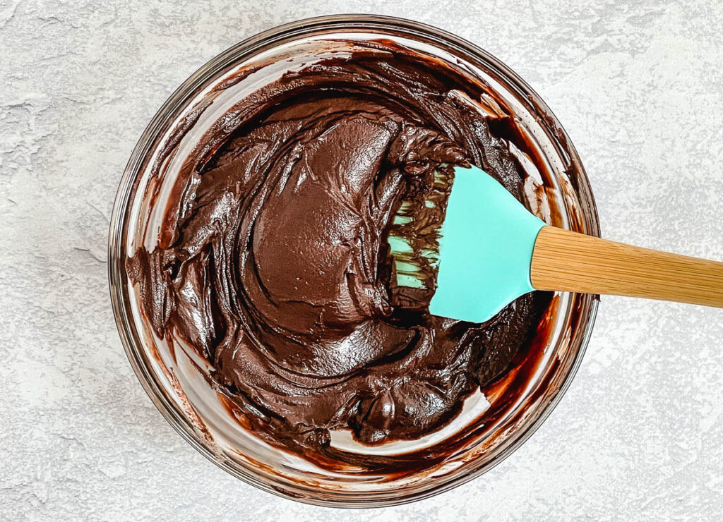 Chocolate ganache in glass bowl with spatula. 
