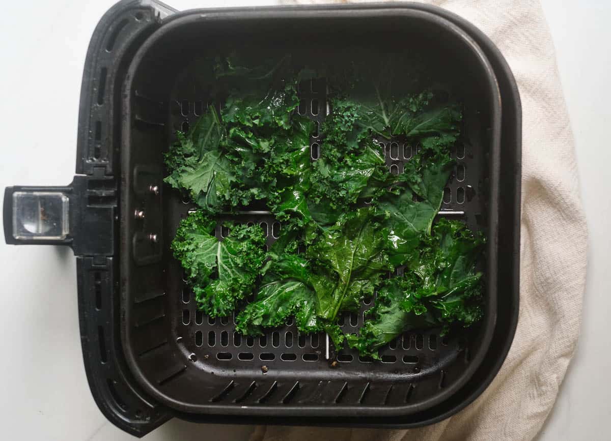 Kale leaves in air fryer basket. 