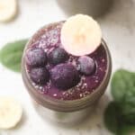 Spinach blueberry smoothie topped with blueberries and a slice of banana.