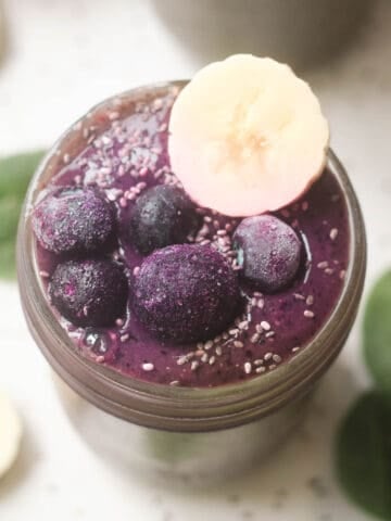 Spinach blueberry smoothie topped with blueberries and a slice of banana.