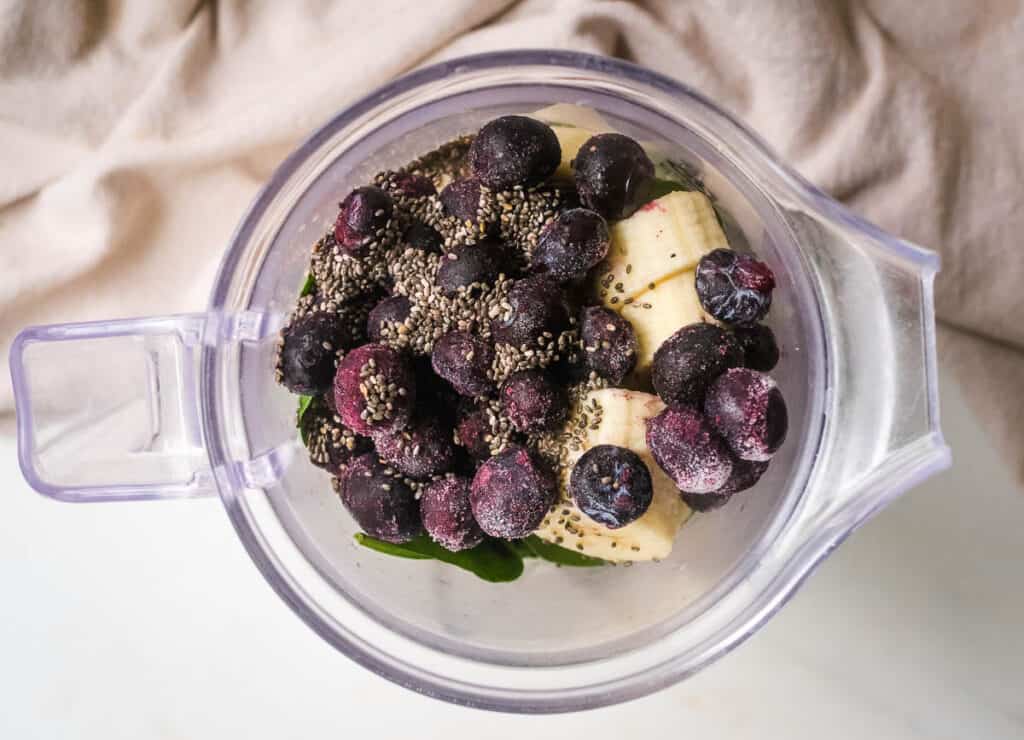 Spinach blueberry smoothie ingredients in blender. 