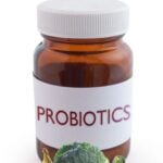 Bottle of probiotics surrounded by healthy vegetables and fruit.