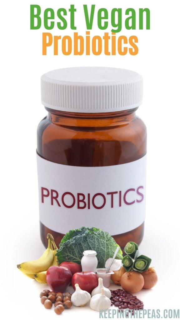 Bottle of probiotics surrounded by healthy vegetables and fruit.