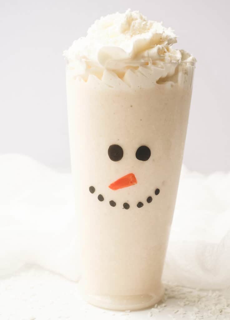 Snowman Christmas smoothie in tall glass with whipped cream.