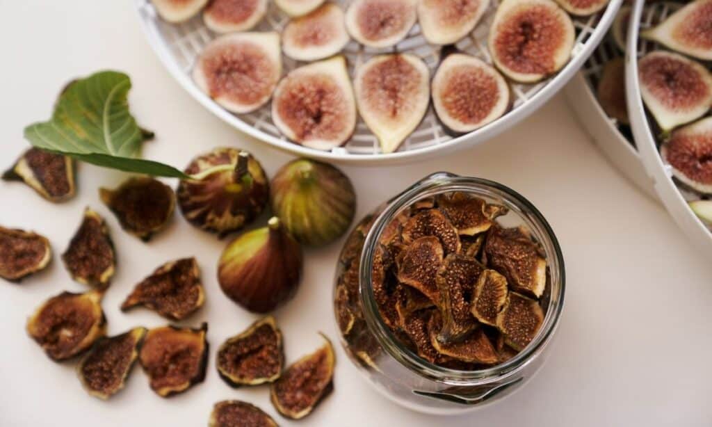 Jar of dried figs beside whole figs, and dried fig pieces. 