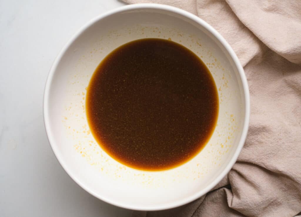 Molasses water, and applesauce whisked together in a white bowl. 