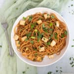 Teriyaki noodles with crispy tofu in white bowl.