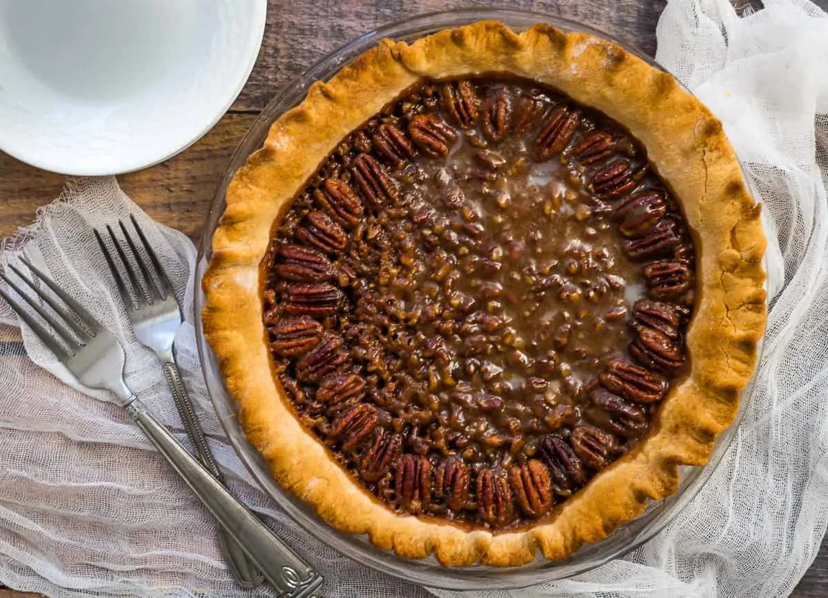 Baked pecan pie with serving plates and forks. 
