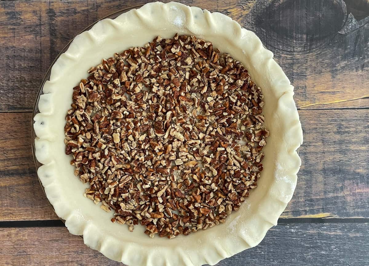 Chopped pecans on the bottom of an unbaked pie crust.