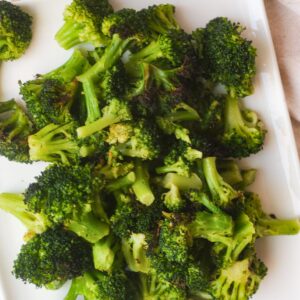 Roasted broccoli florets on white plate.