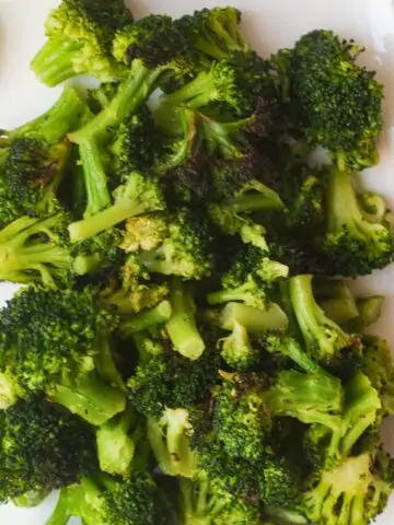 Roasted broccoli florets on white plate.