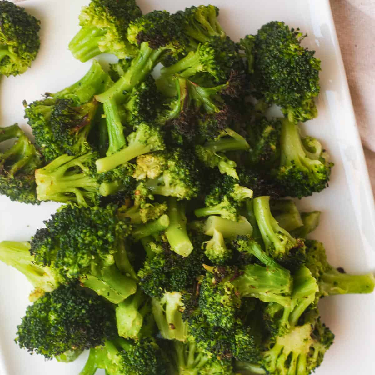 Roasted broccoli florets on a white plate.