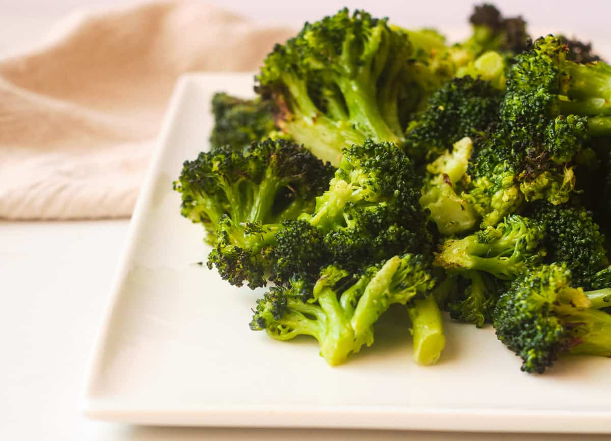 Air fried broccoli florets on white plate. 