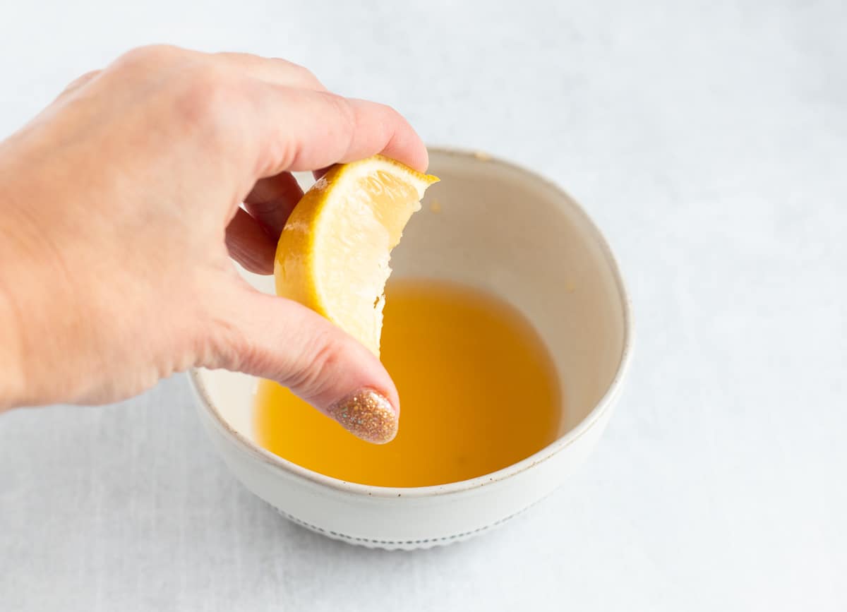 Squeezing lemon juice into bowl of orange juice. 