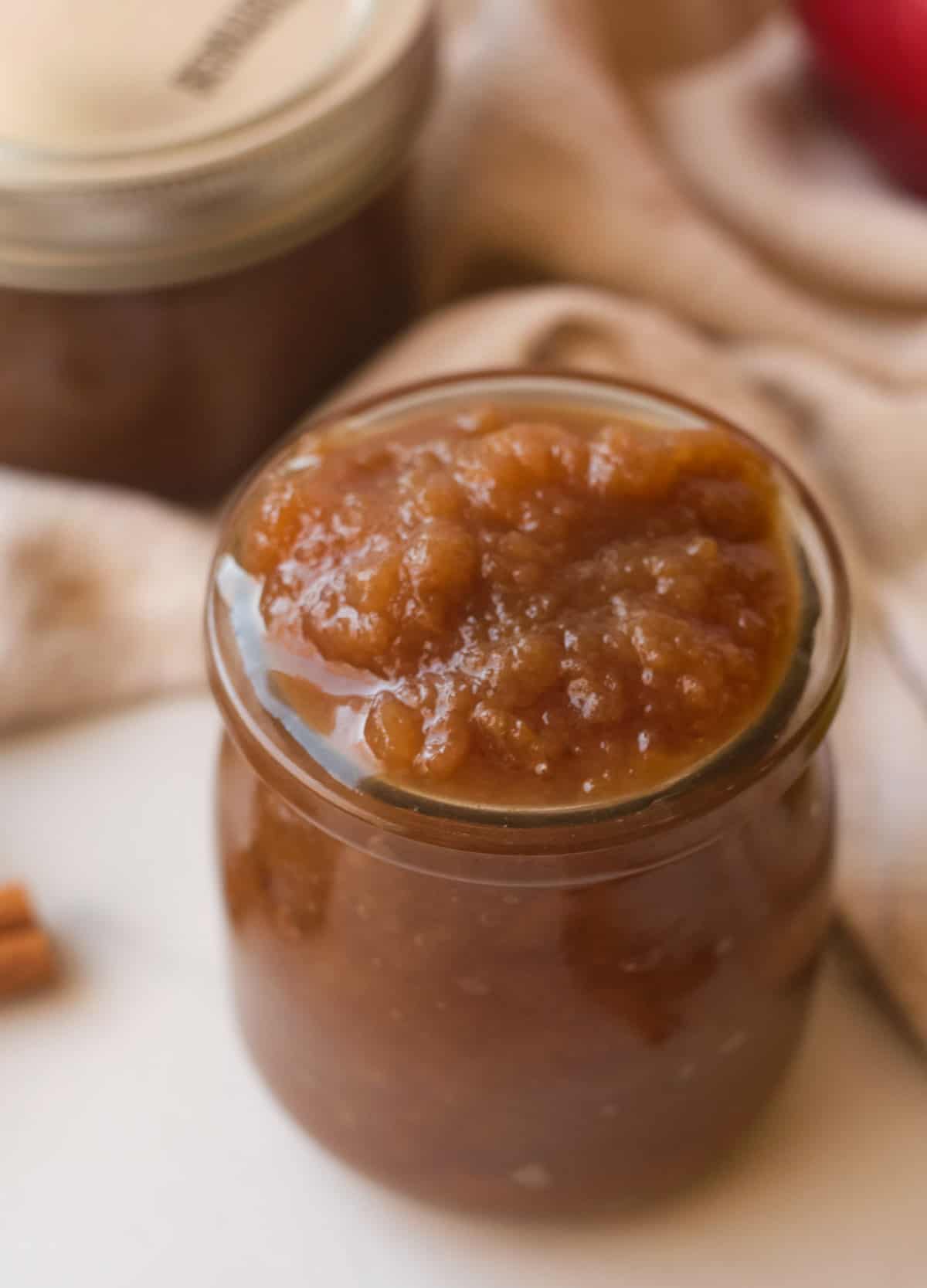Thick apple butter in small glass jar. 