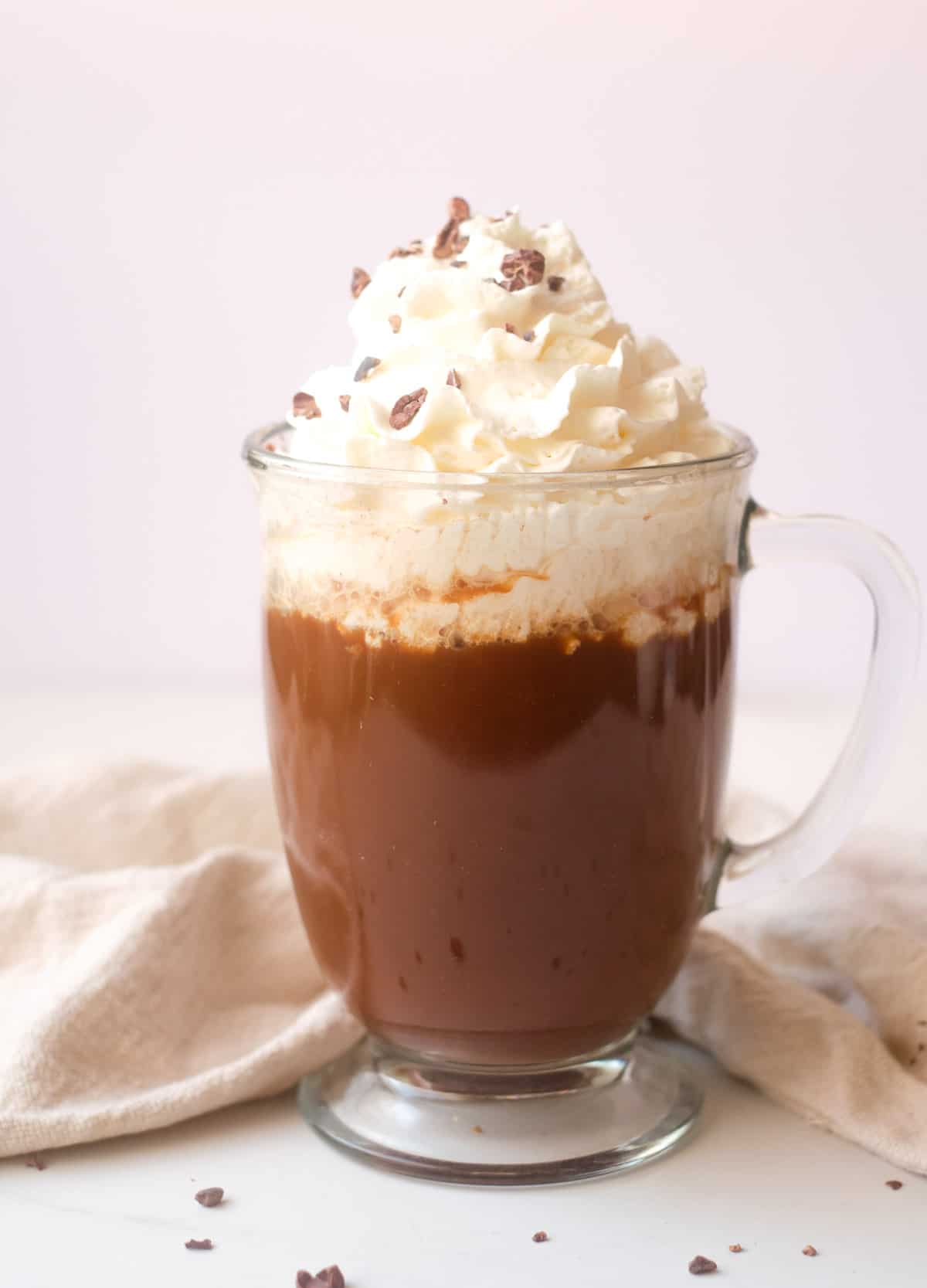 Mocha latte in glass mug topped with whipped cream and chocolate shavings. 