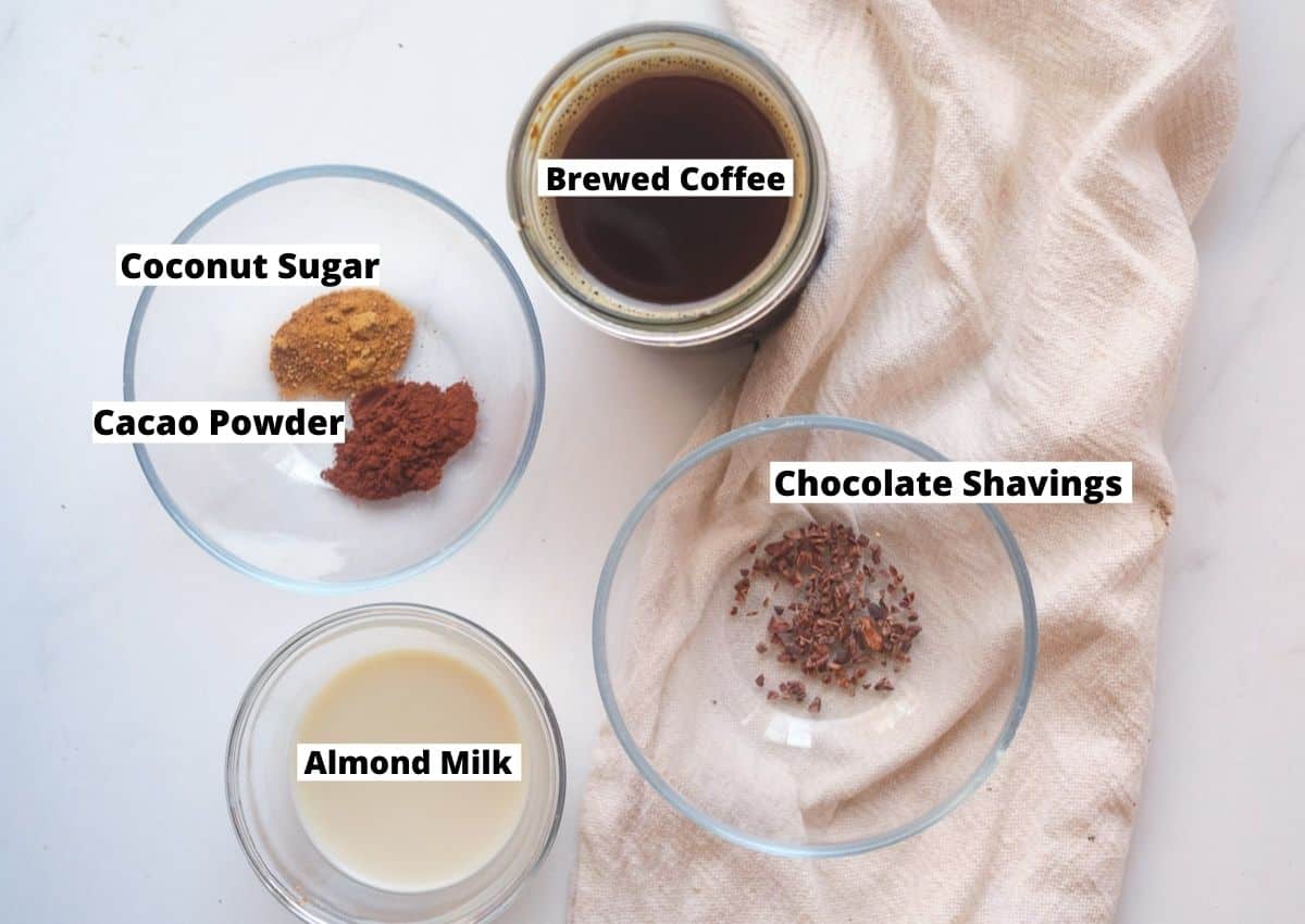 Ingredients for a mocha latte: brewed coffee, coconut sugar, cacao powder, almond milk, and chocolate shavings.