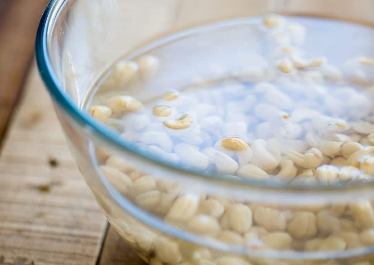 Cashews soaking in a glass bowl filled with water. 