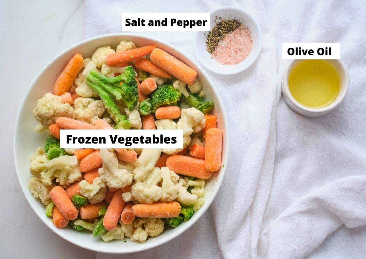 Mixed frozen vegetables in bowl with a side of salt and pepper, and olive oil. 