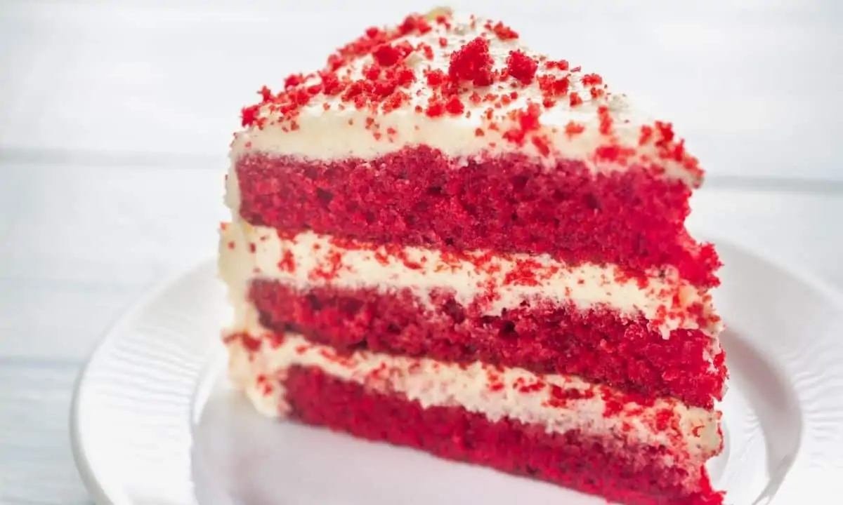 Slice of red velvet cake on white plate.