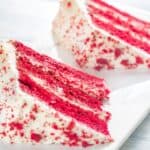 Two slices of vegan red velvet cake on a white plate.