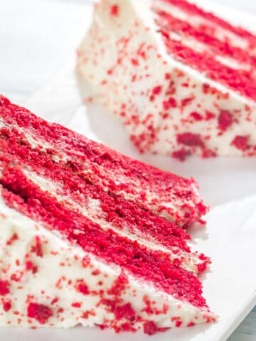 Two slices of vegan red velvet cake on a white plate.