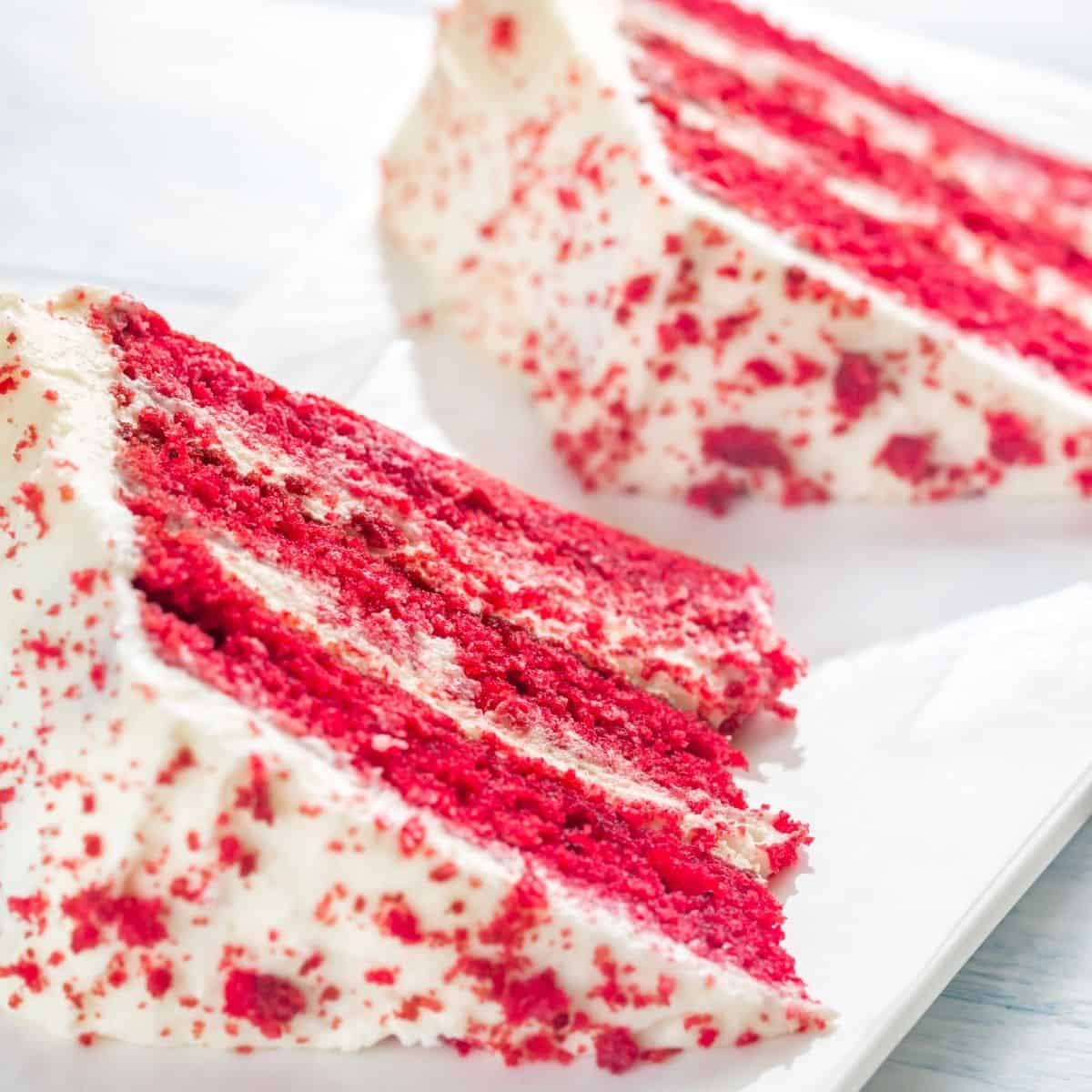 Two slices of vegan red velvet cake on a white plate. 