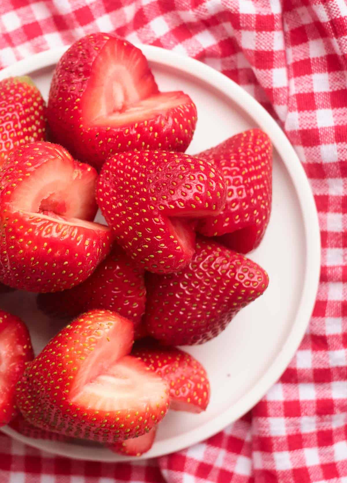 Strawberries but in heart shapes on white plate.