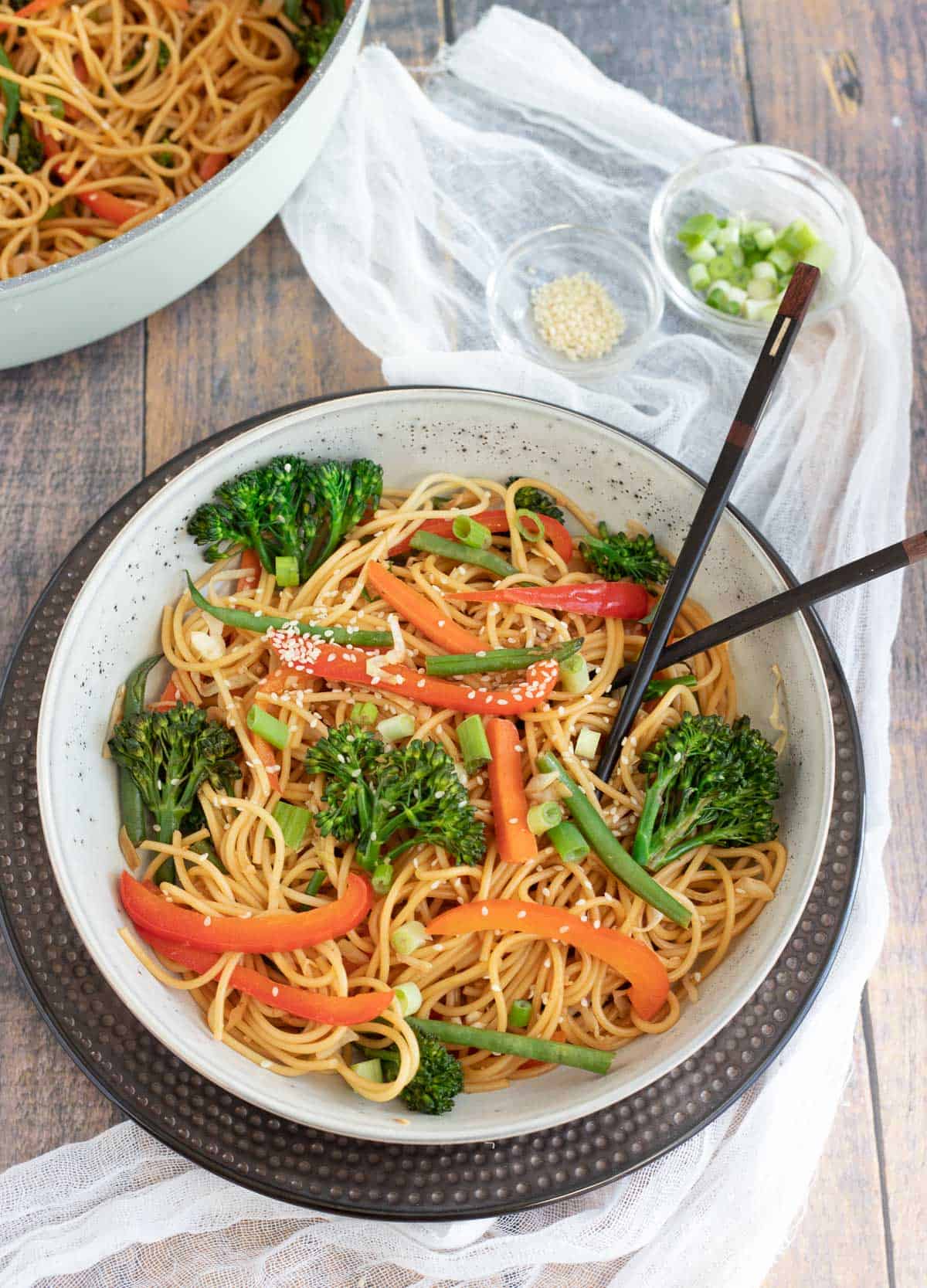 Chow mein noodles with vegetables in bowl with chopsticks.