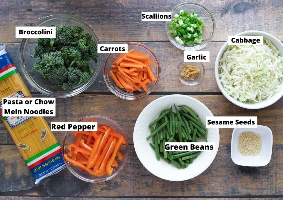 Ingredients for vegan chow mein: noodles, broccolini, carrots, red peppers, green peans, cabbage, green onions, garlic, sesame seeds.