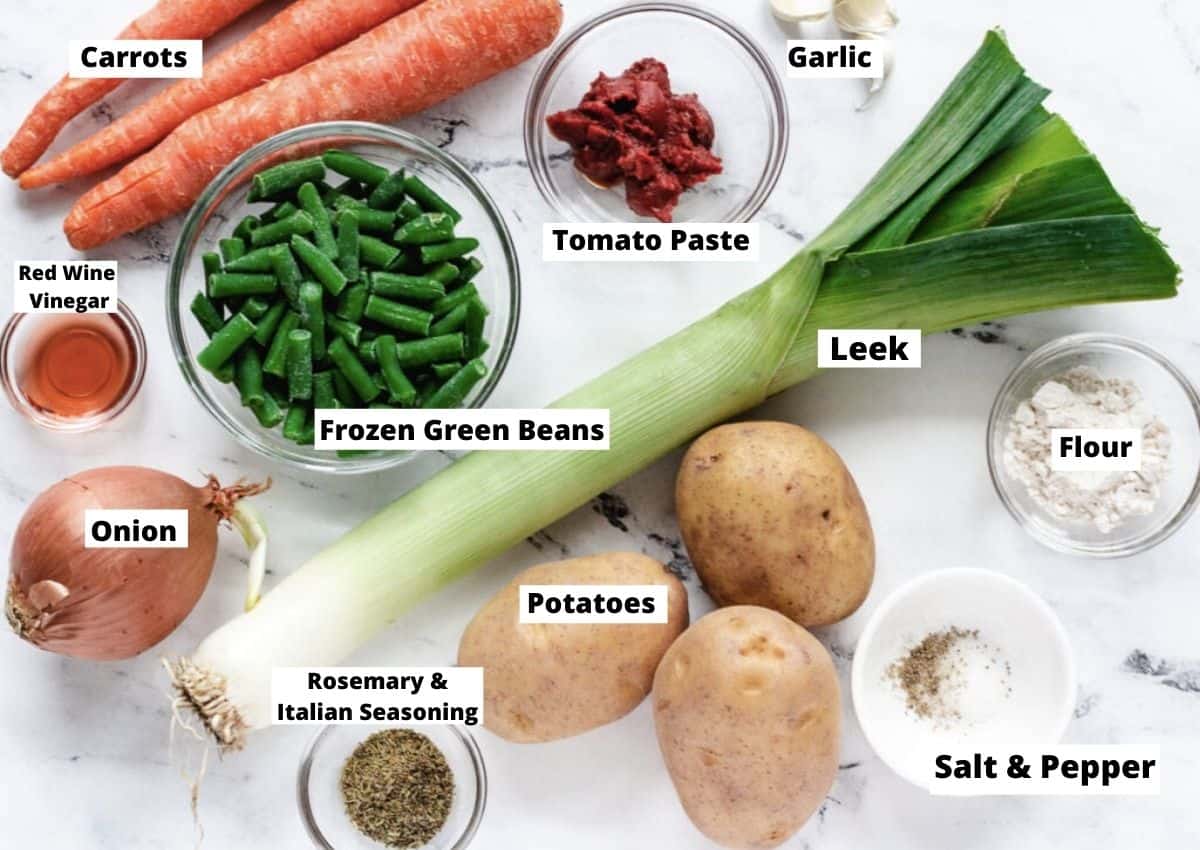 Ingredients for Vegan Irish Stew: Carrots, tomato paste, garlic, leek, flour, salt and pepper, potatoes, rosemary, and Italian Seasoning, onion, red wine vinegar, and frozen green beans.