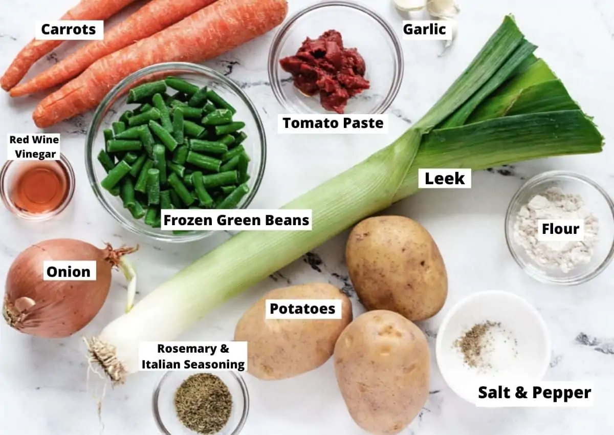 Ingredients for Vegan Irish Stew: Carrots, tomato paste, garlic, leek, flour, salt and pepper, potatoes, rosemary, and Italian Seasoning, onion, red wine vinegar, and frozen green beans.