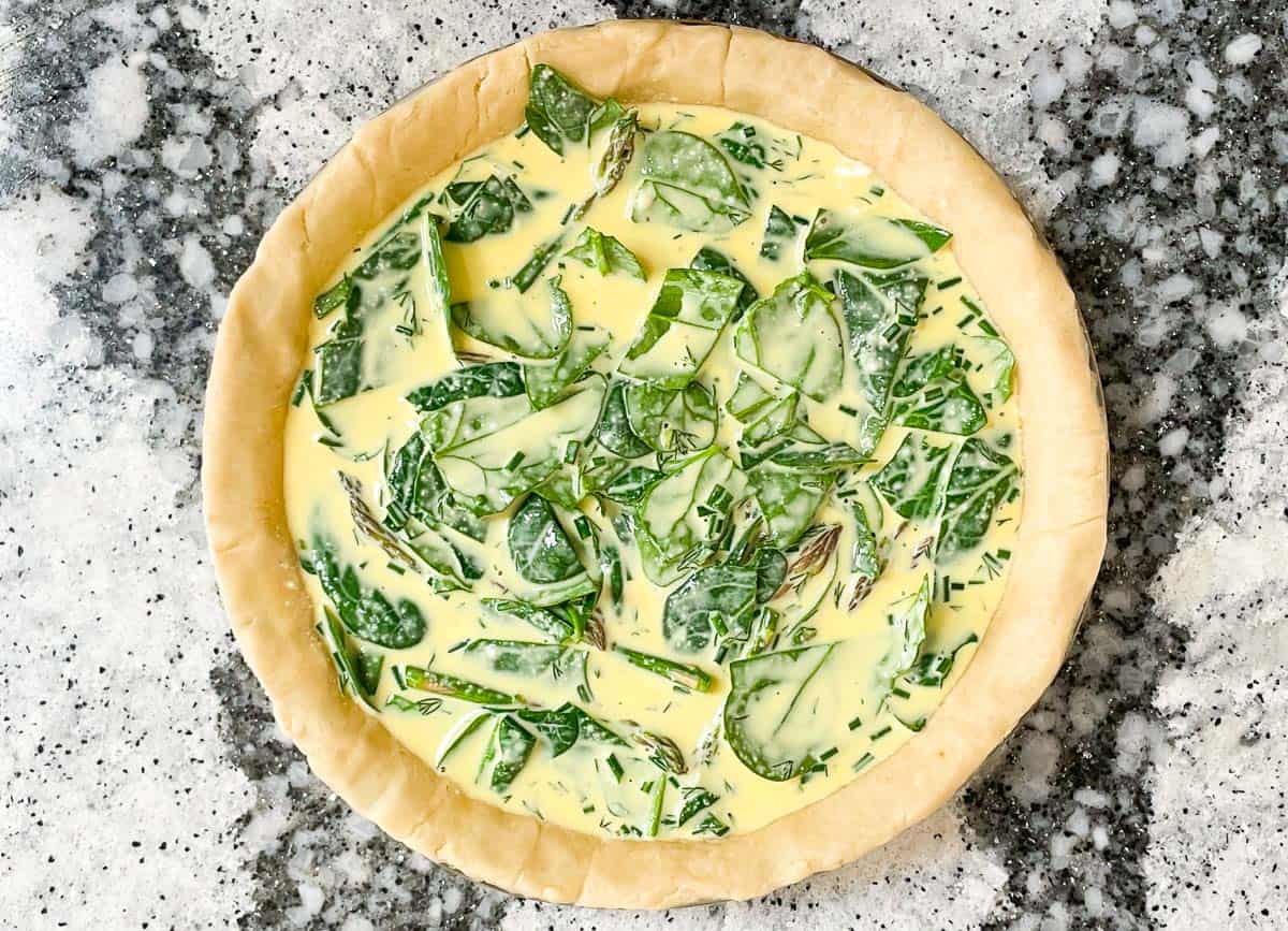 Unbaked pie shell filled with just egg mixture, spinach and asparagus. 