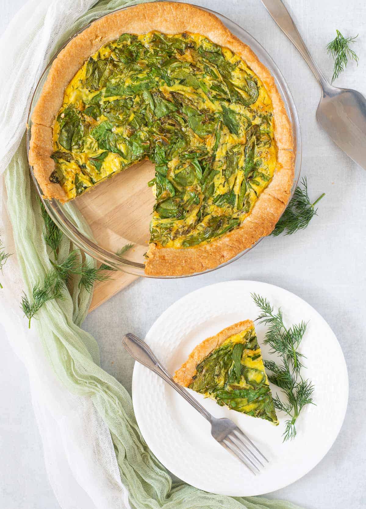 Vegan quiche with a slice cut out and placed on a plate. 