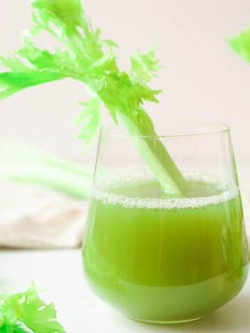 Glass of celery juice with stalk.