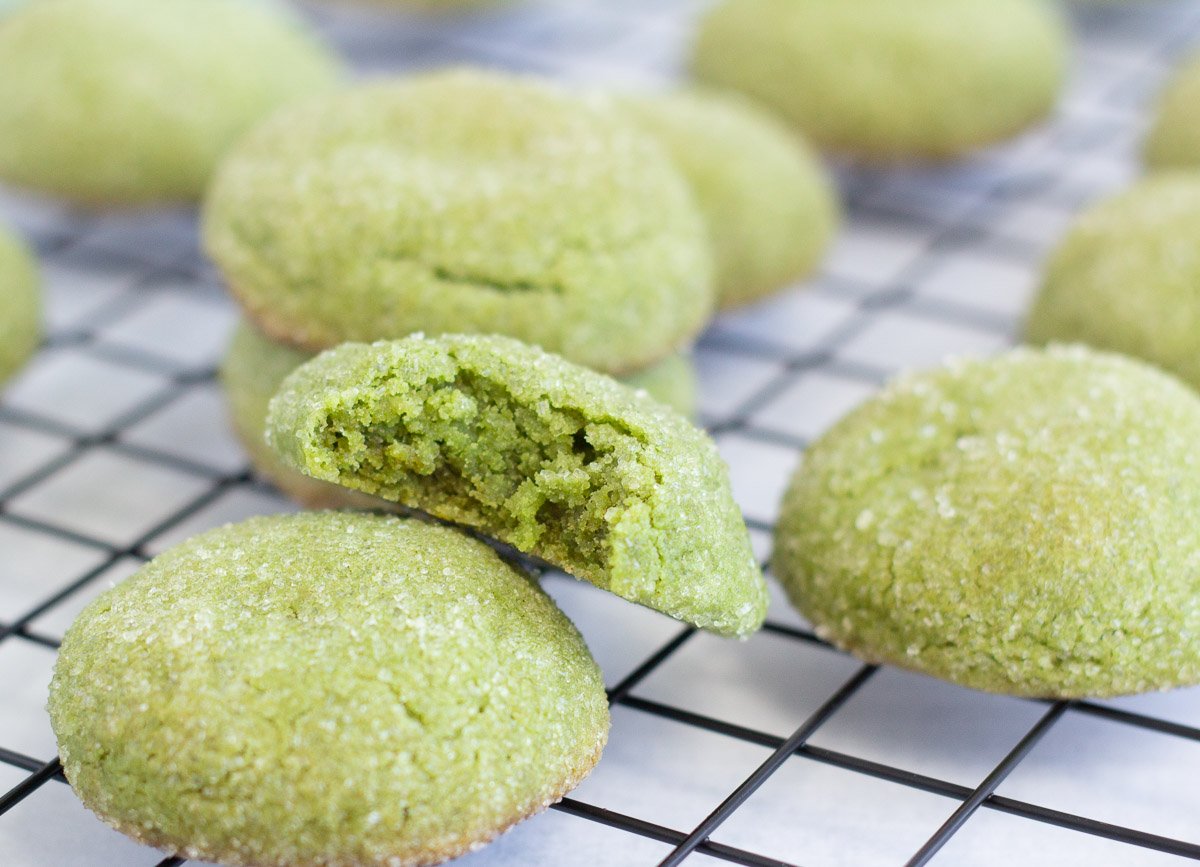 Matcha cookies on cooling rack with a bite taken out of one.
