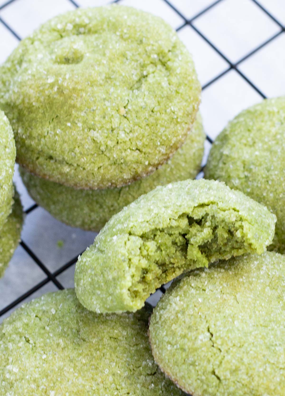 Matcha cookies stacked on top of one another with a bite taken out of one.