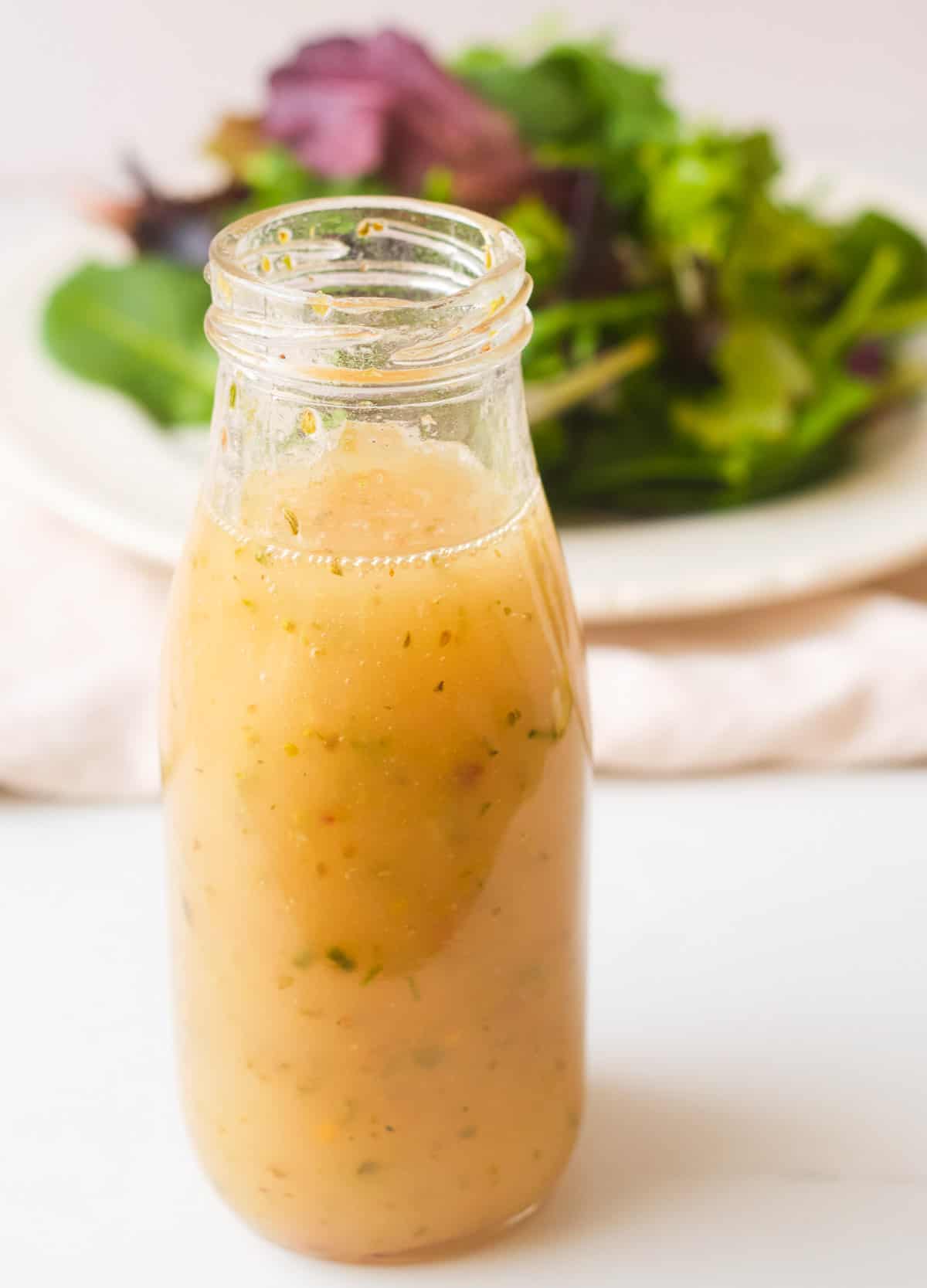 Vegan Italian dressing in a bottle with a side salad. 