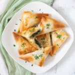 Vegan spanakopita triangles on white square plate.