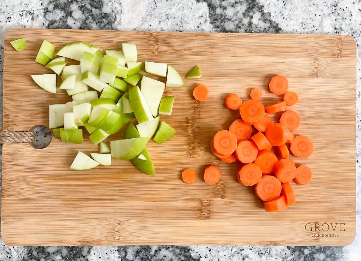 Chopped green apple and chopped carrots on cutting board. 