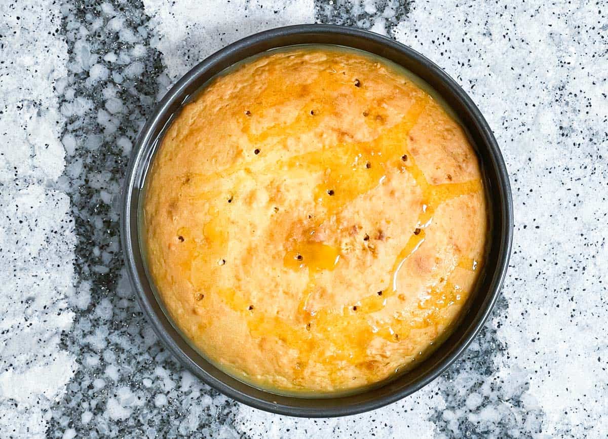 Baked orange cake with holes pocked into it and syrup poured over top.
