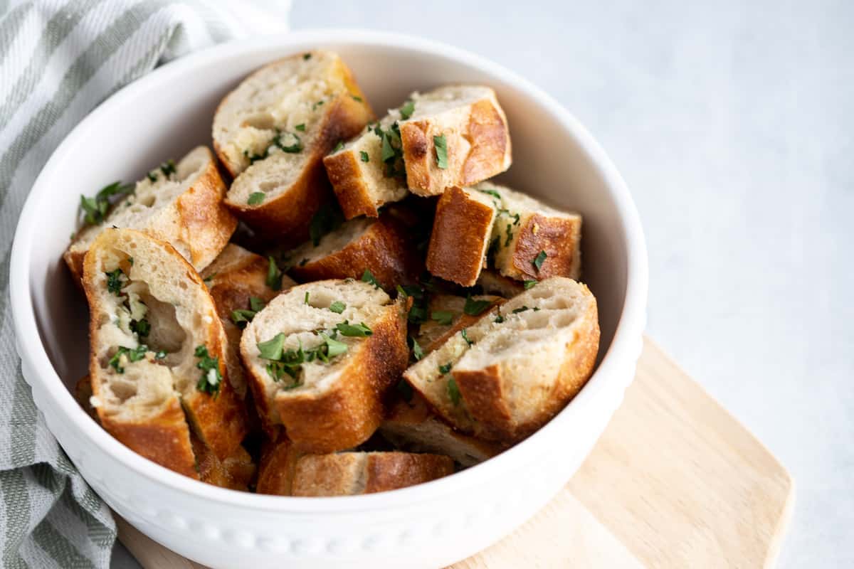 Sliced garlic bread pieces in white bowl. 