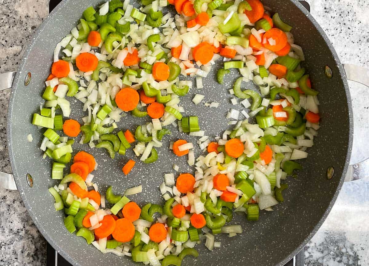 Diced carrots, celery and onions sautéing in pot. 