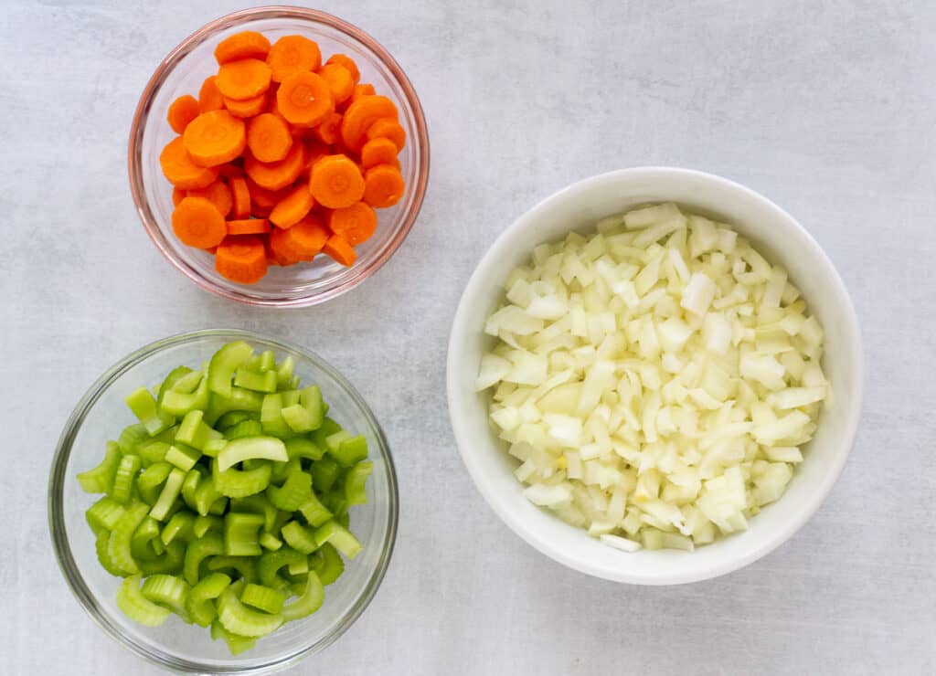 Chopped carrots, celery, and. onion in small bowls. 