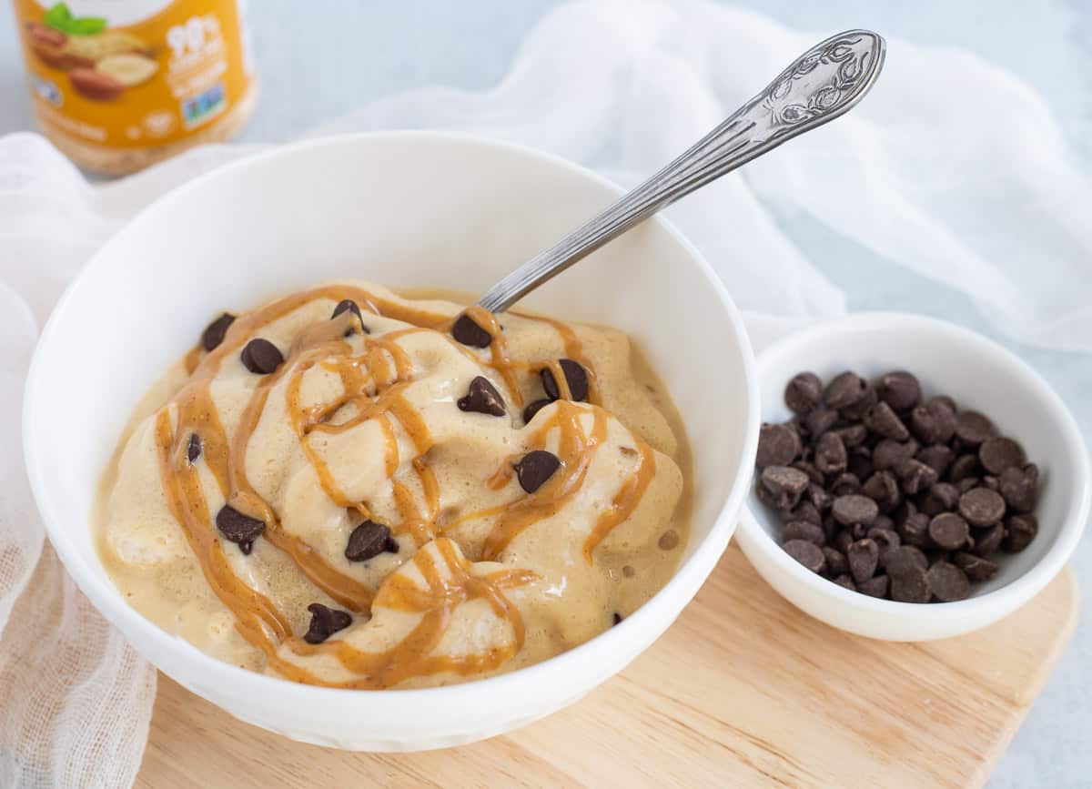 Serving of protein fluff topped with peanut butter and chocolate chips in white bowl. 