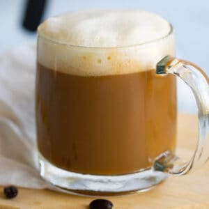 Vanilla soy latte in glass mug topped with foam.