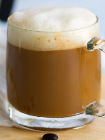 Vanilla soy latte in glass mug topped with foam.