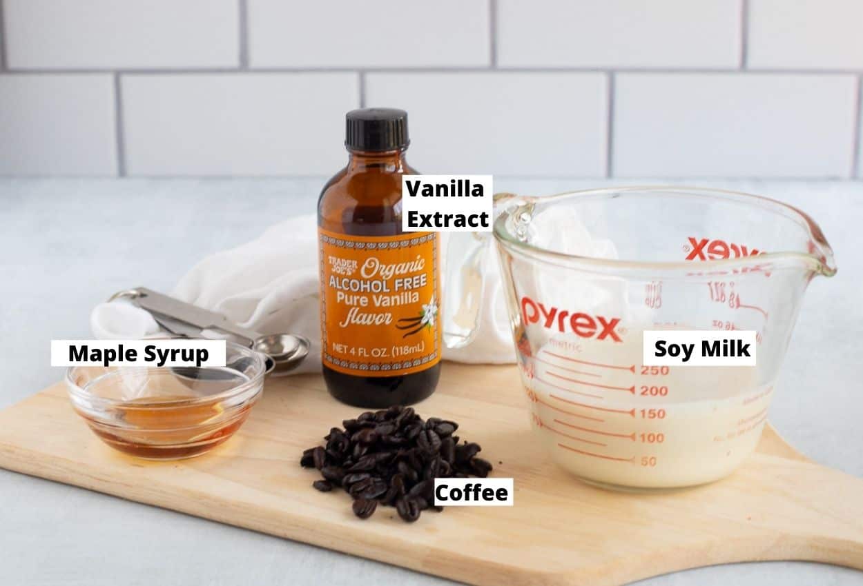 Soy milk, coffee beans, maple syrup, and vanilla extract bottle. 